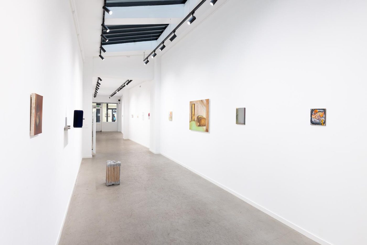 The gallery interior at 24 rue Chapon: a long white room with a skylight and works hung on both walls.